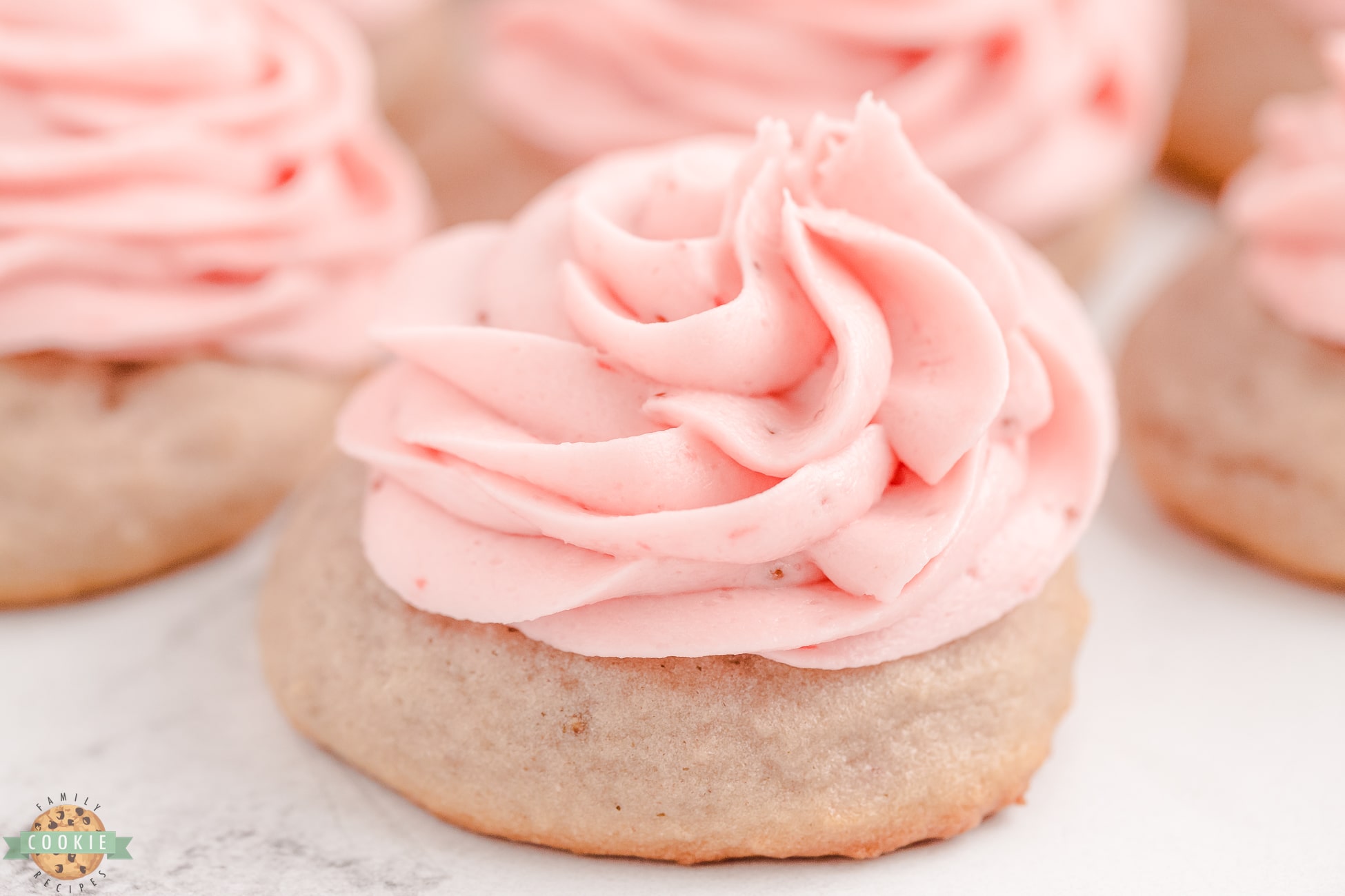 strawberry sugar cookie topped with swirled strawberry buttercream frosting