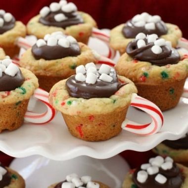 Hot Chocolate Cookie Cups are festive Christmas cookies! Sugar cookie cups filled with fudge, mini marshmallows & sprinkles. Love the candy cane handle! Hot Chocolate Cookie Cups are sugar cookies perfect for the holidays. 