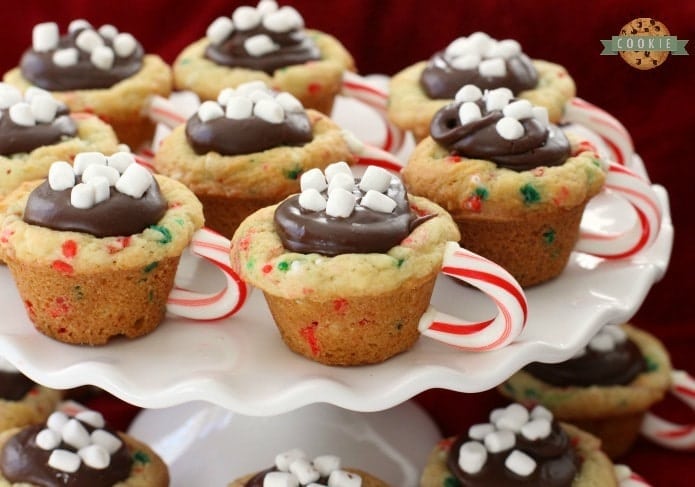 Hot Chocolate Cookie Cups are festive Christmas cookies! Sugar cookie cups filled with fudge, mini marshmallows & sprinkles. Love the candy cane handle! Hot Chocolate Cookie Cups are sugar cookies perfect for the holidays. 