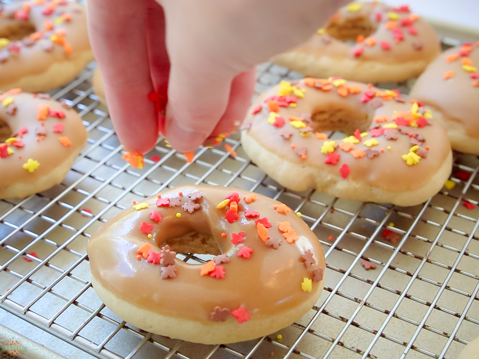 adding sprinkles to the top of maple donut cookies