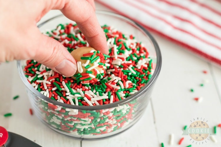 rolling sugar cookies in Christmas jimmies sprinkles