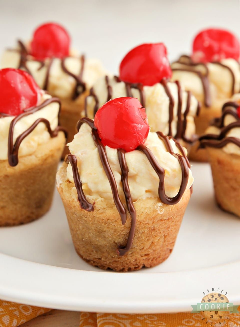 Banana Split Cookie Cups taste like your favorite banana split dessert in cookie form! Banana flavored cookies filled with pineapple cream and topped with chocolate and a cherry! 