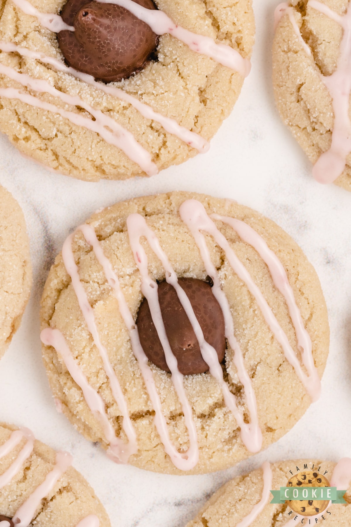 Almond Kiss Cookies made with almond extract and Hershey kisses with almonds! Drizzled with a simple raspberry glaze, these make a fantastic alternative to the traditional peanut butter blossoms!