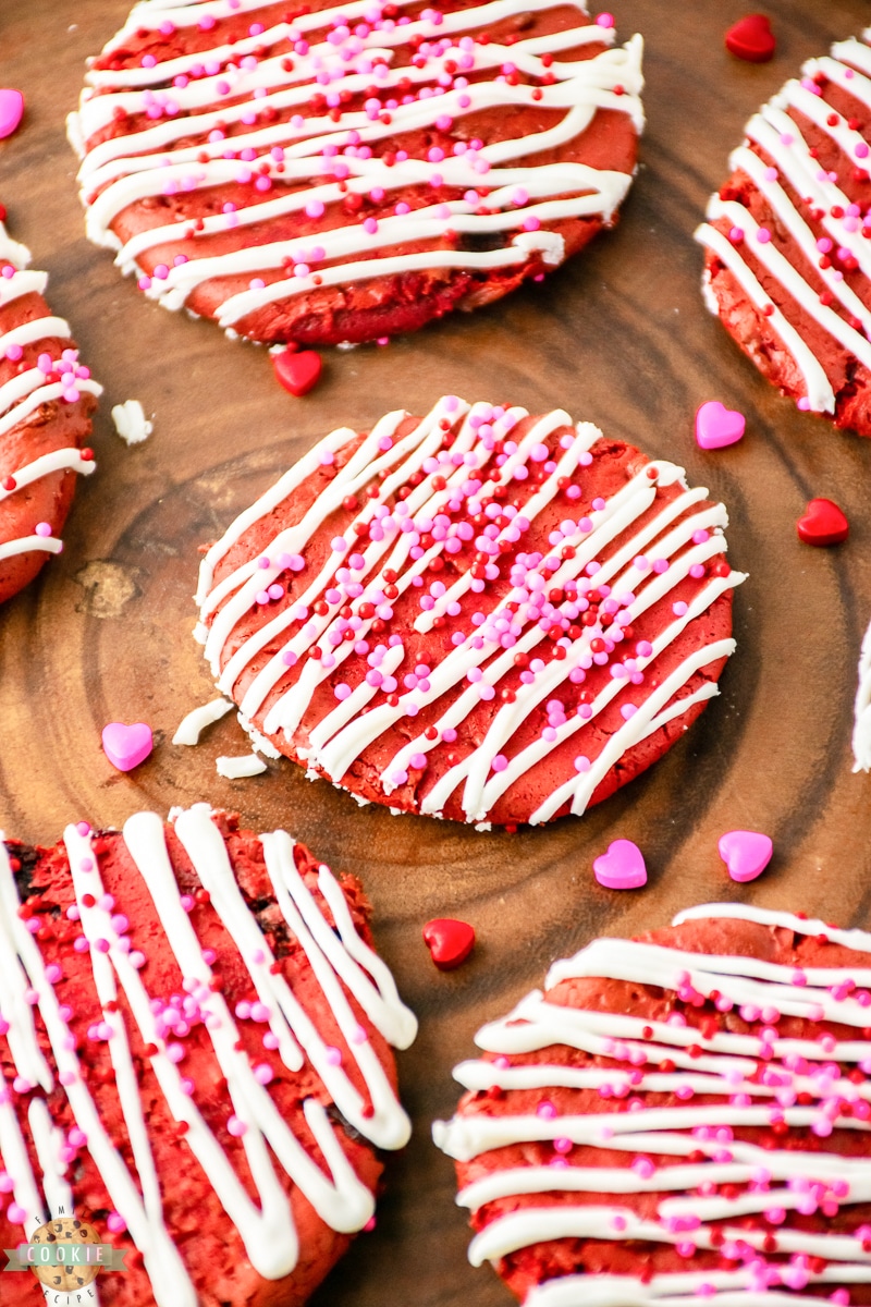 red velvet cake mix cookies with a vanilla drizzle and Valentines sprinkles on a wooden table