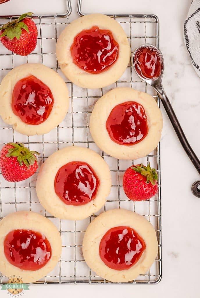 cooling rack with several strawberry thumbprint cookies on it