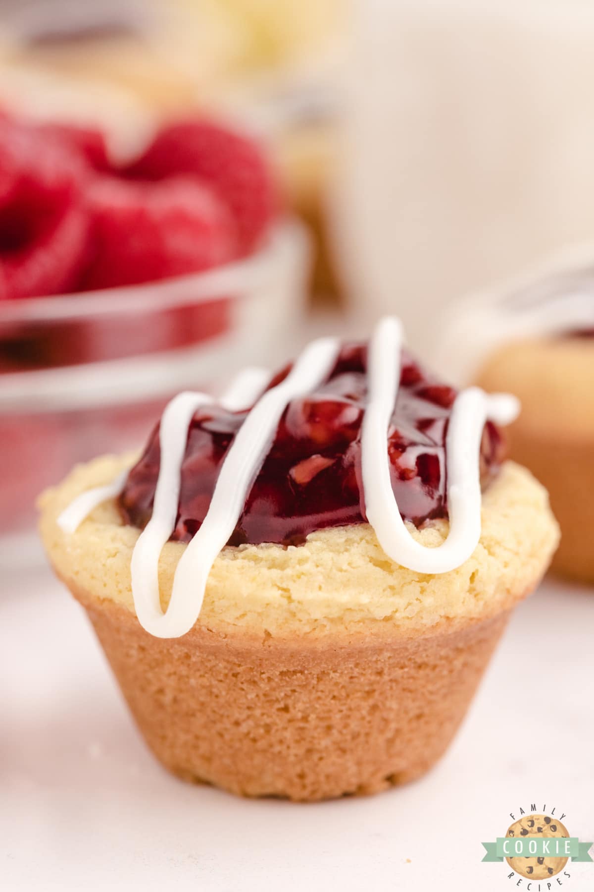 Lemon Raspberry Cookie Cups are made with a simple lemon cookie recipe and raspberry pie filling. Drizzle a little white chocolate on top for a bite sized cookie cup recipe that is impressive and delicious!