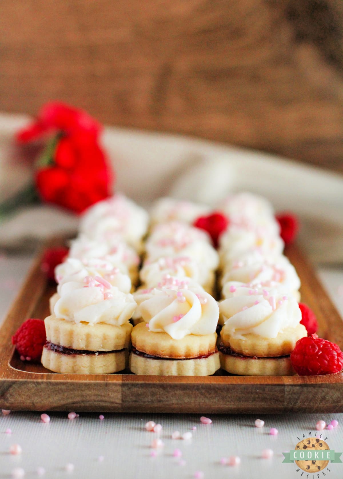 Shortbread cookie sandwiches filled with raspberry jam and topped with buttercream frosting. 