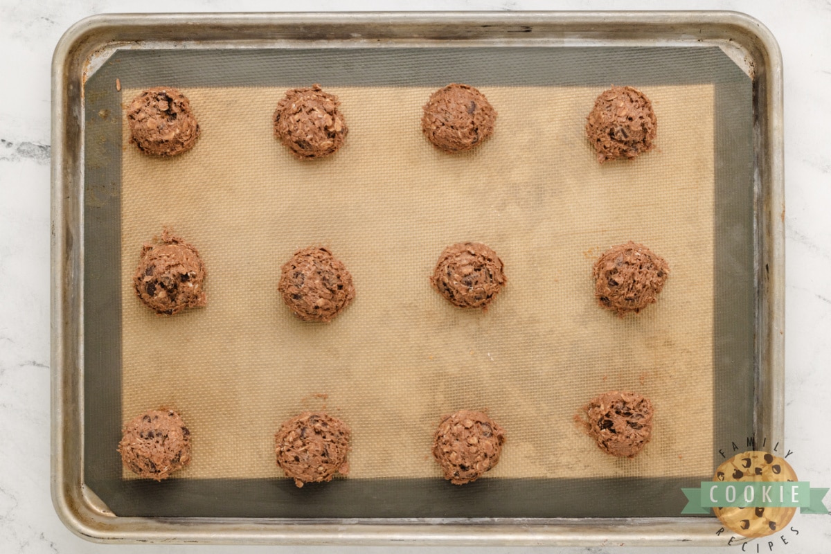 Double chocolate oatmeal cookie dough scooped onto a cookie sheet. 