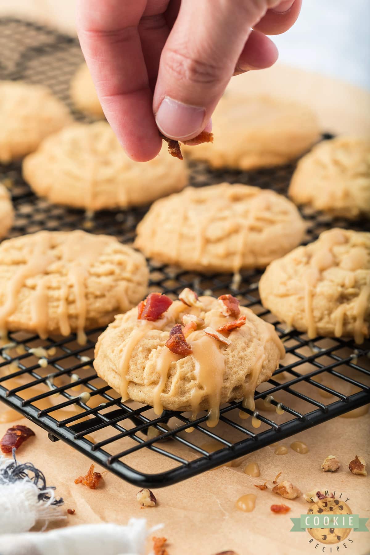 Adding crumbled bacon and nuts to the top of the cooled cookies. 