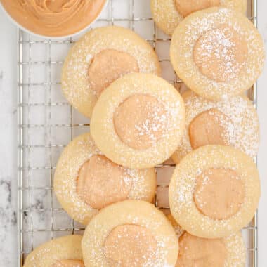 peanut butter thumbprint cookies dusted with powdered sugar on a cooling rack