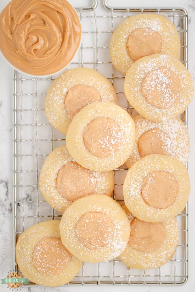 peanut butter thumbprint cookies dusted with powdered sugar on a cooling rack