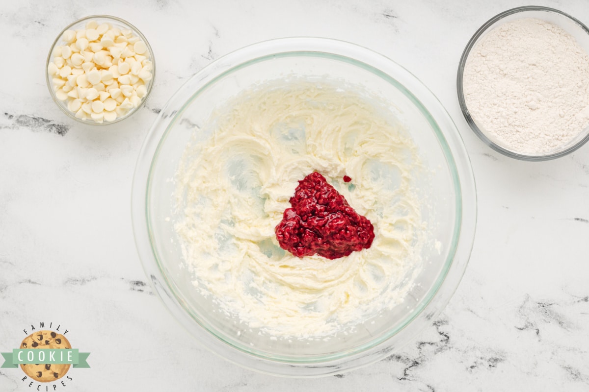 Adding frozen raspberry mixture to creamed butter and sugar. 