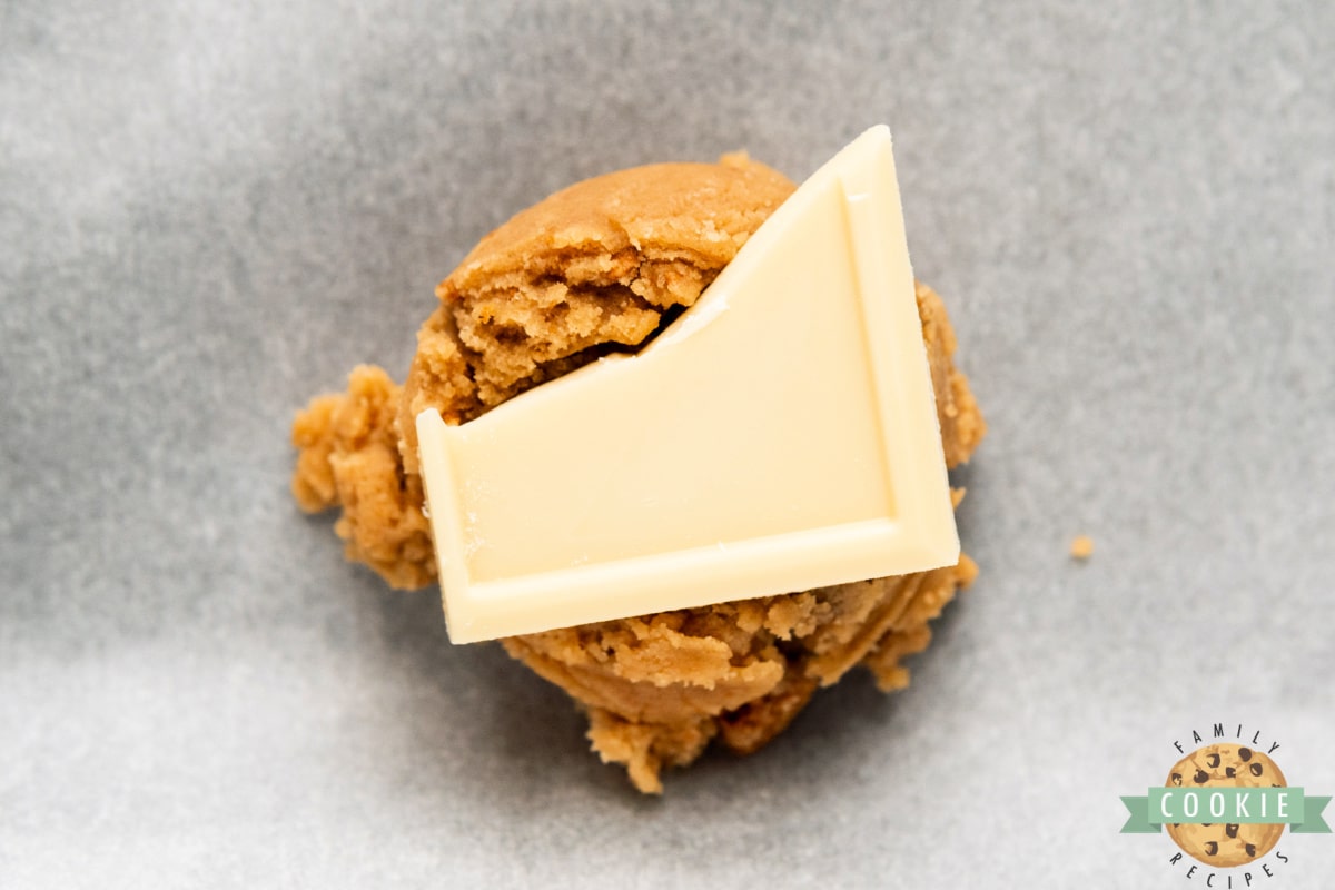 Adding white chocolate to the center of each ball of cookie dough.