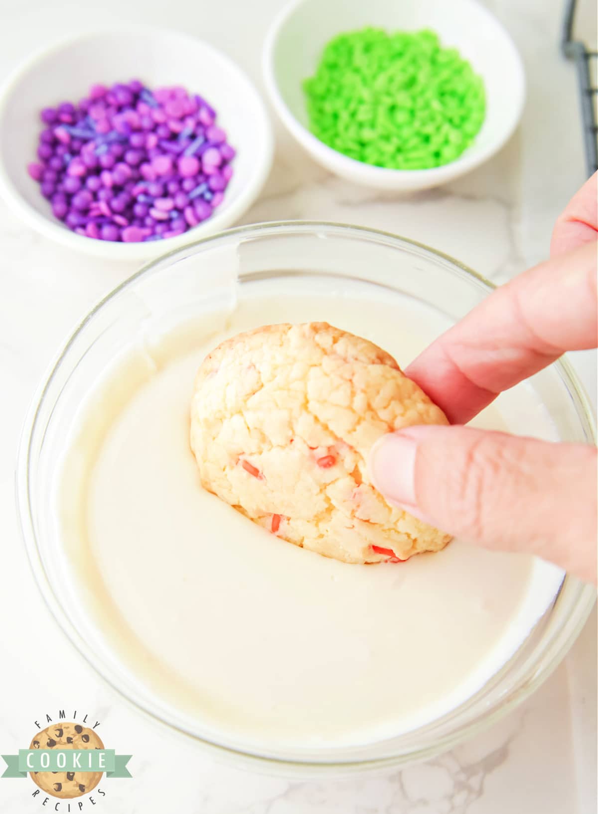 Dipping cookie in vanilla frosting. 