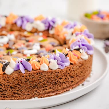 Halloween cookie cake with purple and orange rosette frosting and sprinkles