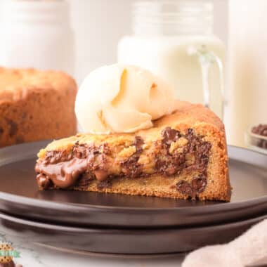 Nutella cookie cake topped with ice cream on a black plate