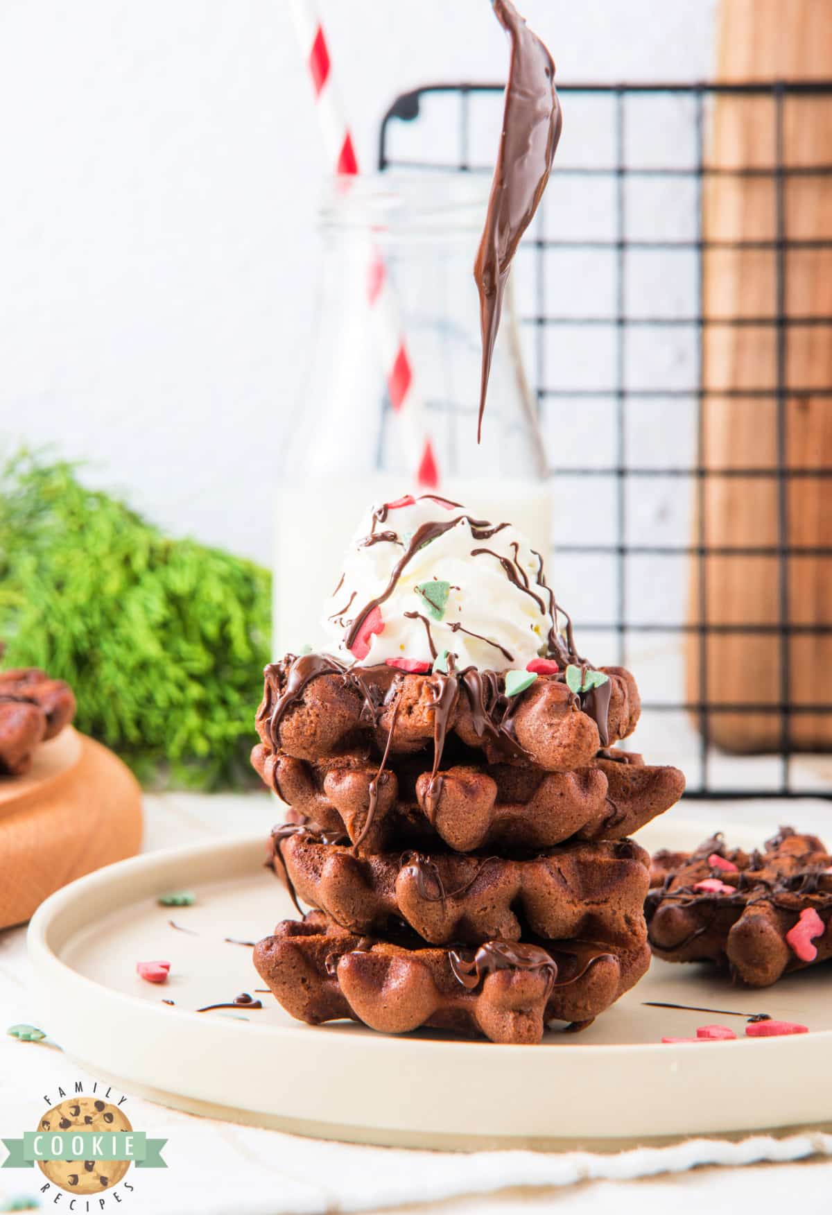 Stack of chocolate waffle cookies with whipped cream on top. 