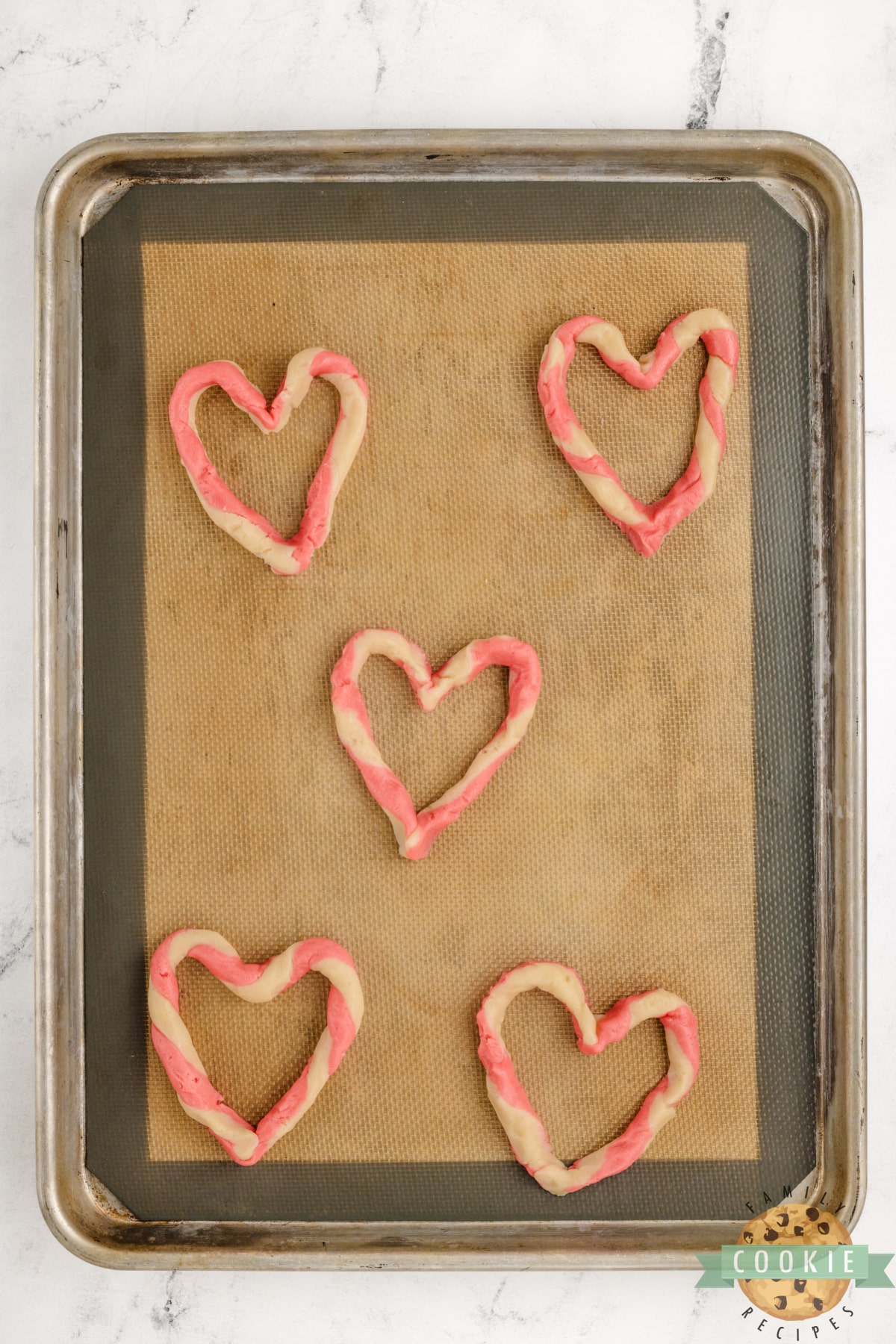 Pink and white dough twisted into a heart shape. 