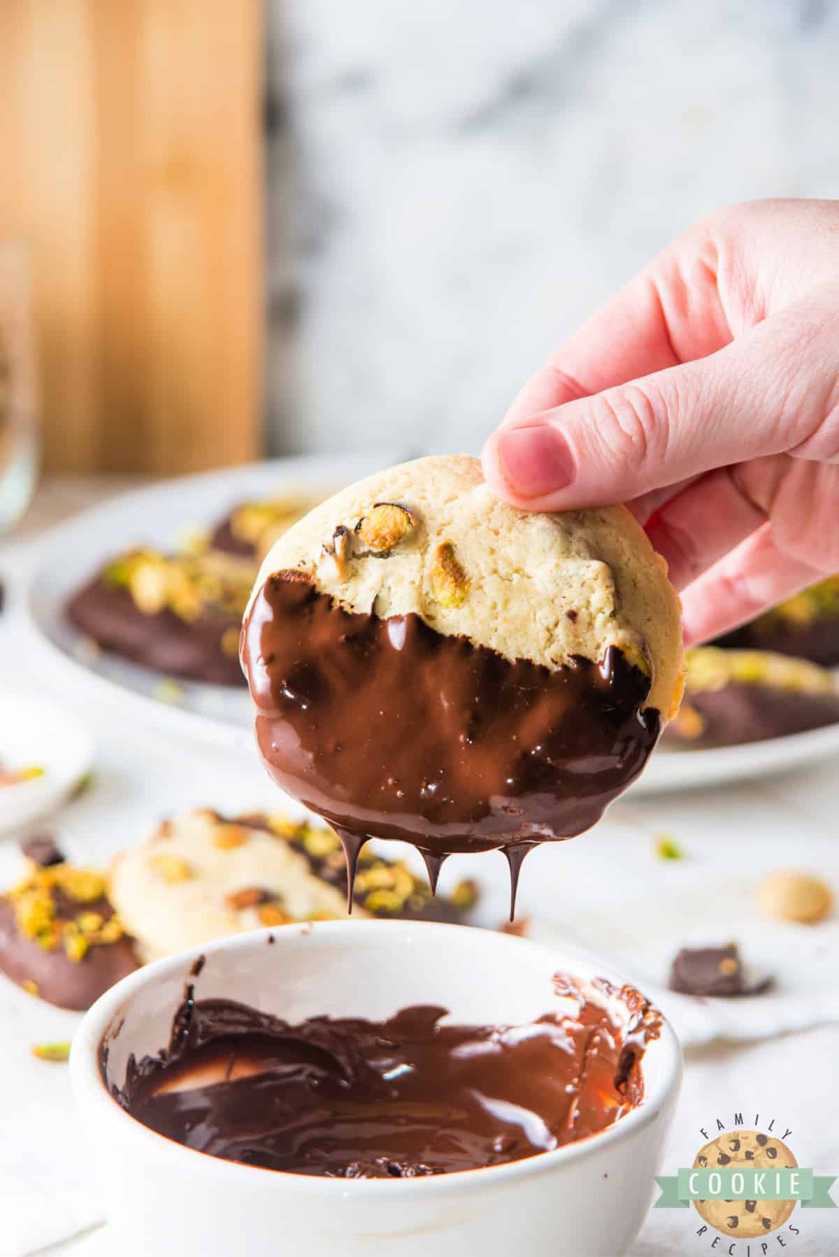 Dipping a pistachio cookie in melted dark chocolate.