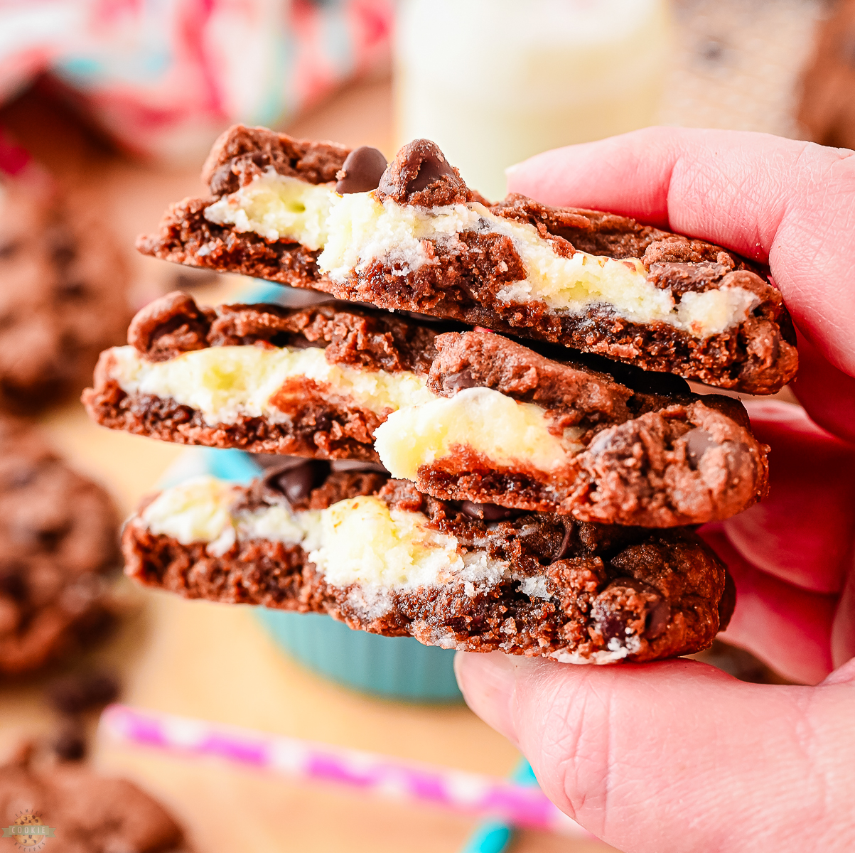 holding three cream cheese and chocolate cookies broken in half