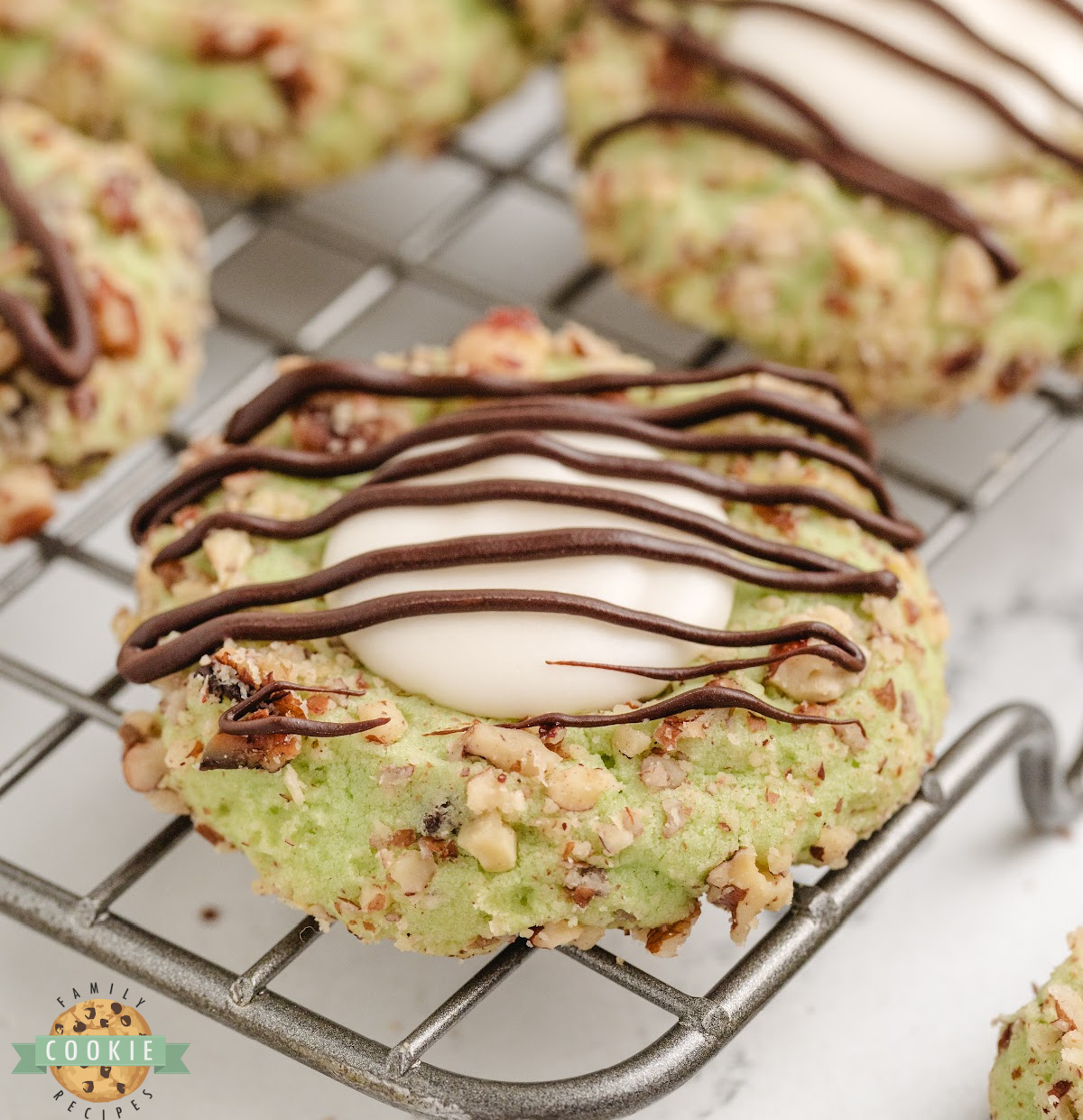 Soft pistachio thumbprint cookies with chocolate chips, pecan coating, and vanilla filling—easy to make and absolutely delicious!