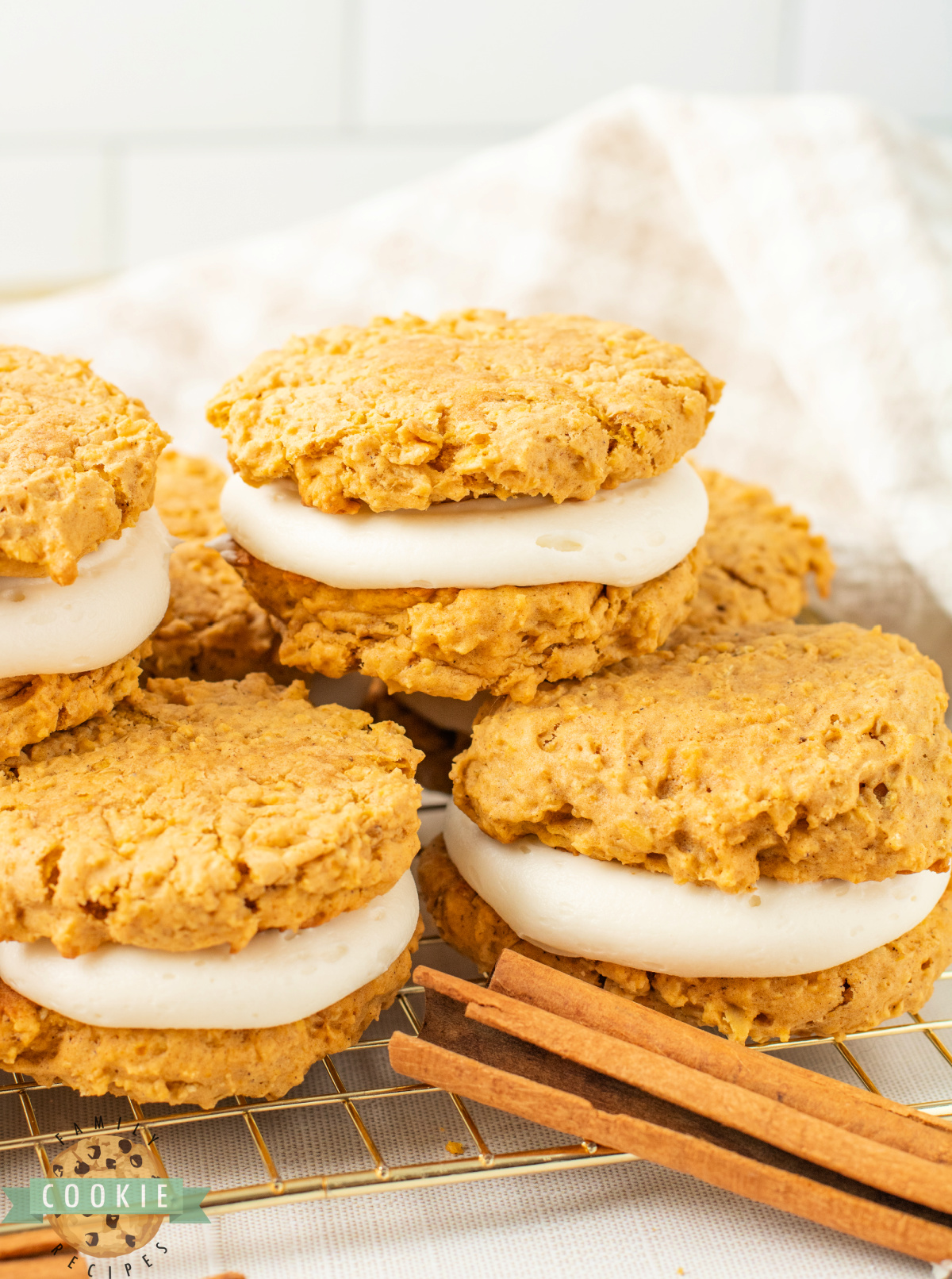 Stack of pumpkin oatmeal sandwich cookies filled with cream cheese frosting.