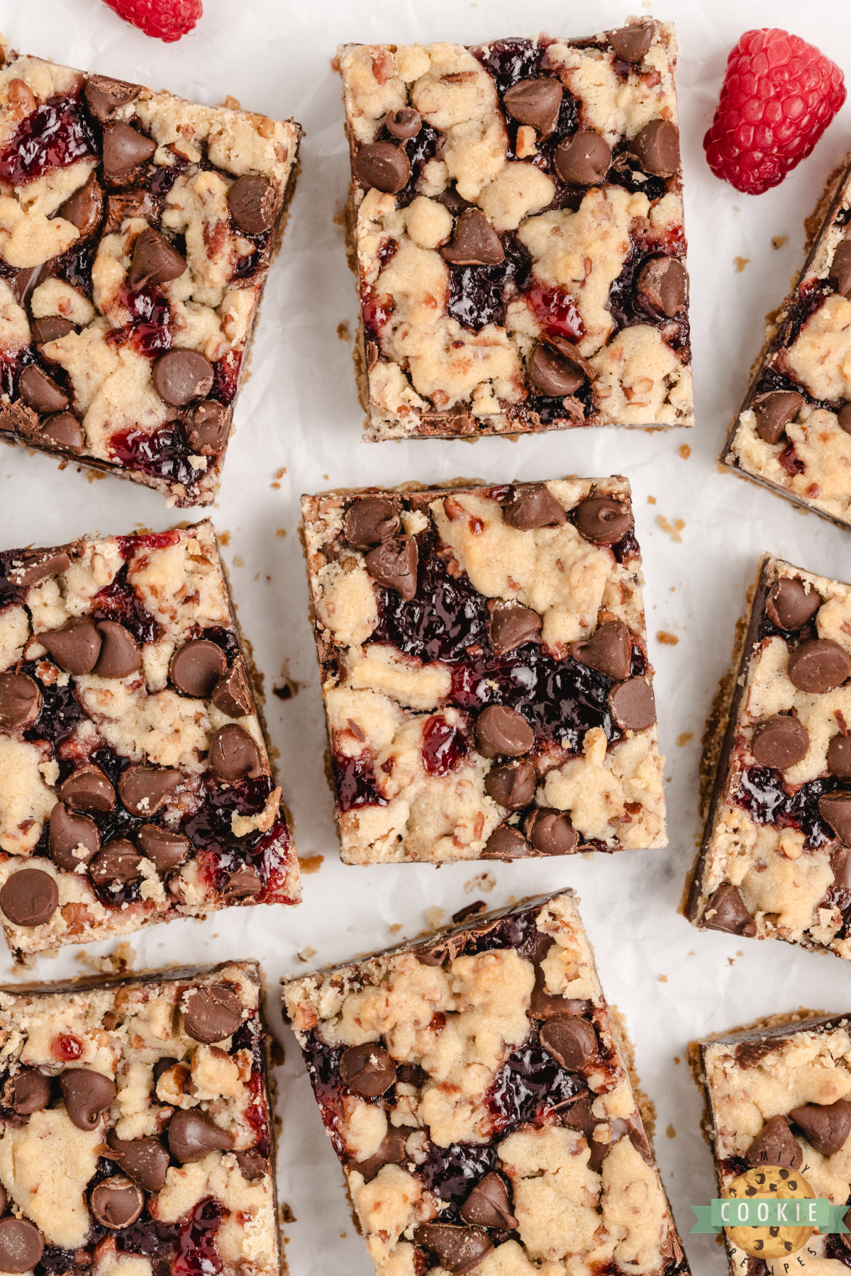 Squares of chocolate raspberry shortbread bars arranged on parchment paper.