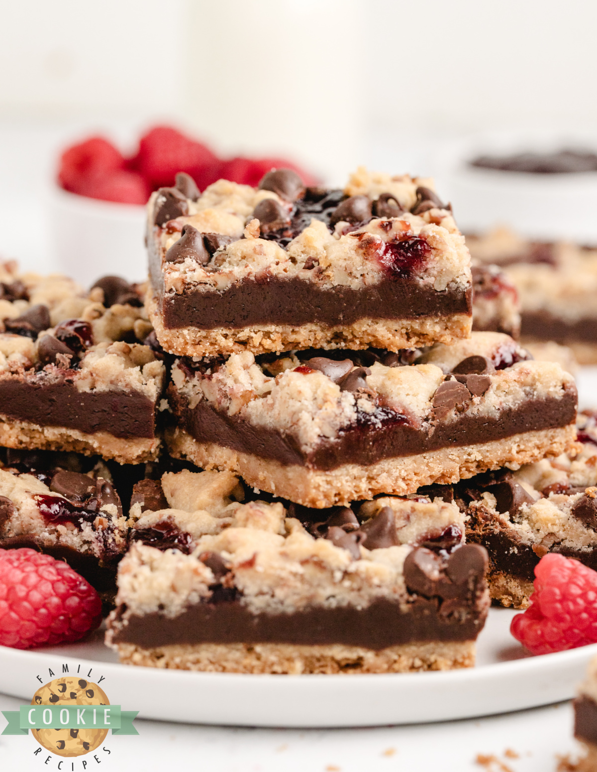 Shortbread bars topped with chocolate, raspberry jam, and nuts.