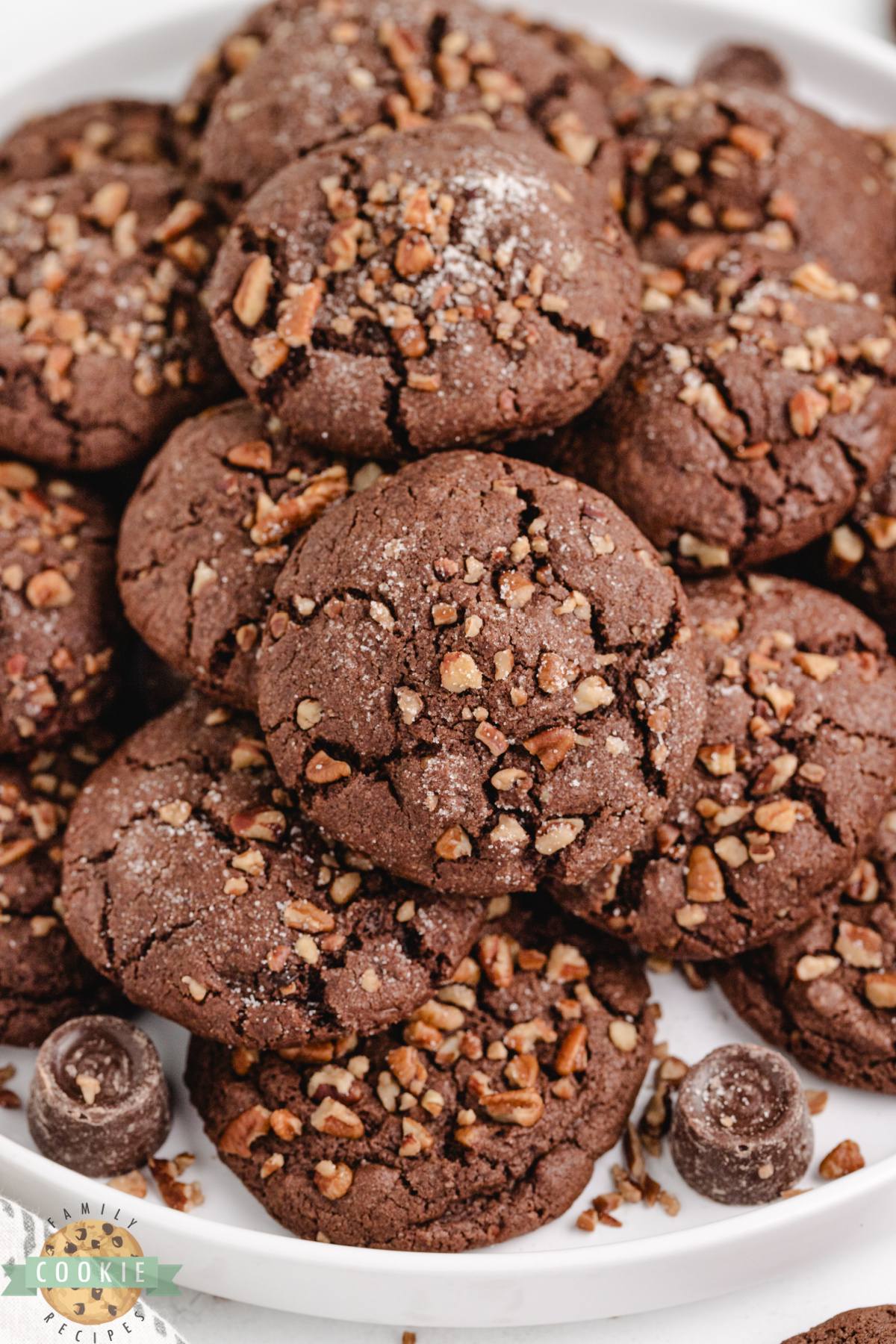 Chocolate caramel cookies with crispy pecan edges and soft chocolate centers displayed on a plate.
