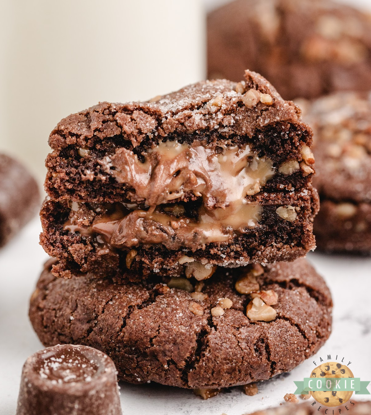 Stack of chocolate caramel pecan cookies with gooey caramel oozing from the center.