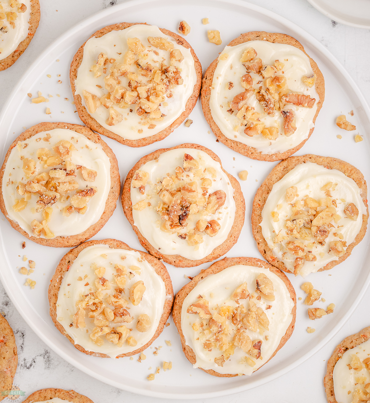 plate of Carrot Cake Cookies topped with cream cheese frosting and walnuts