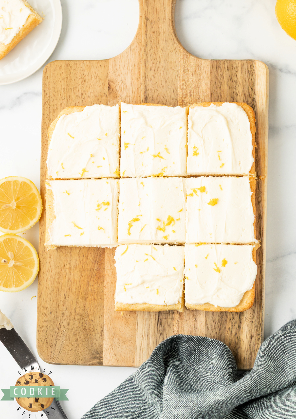 Lemon cookie bars being cut into squares with a knife.