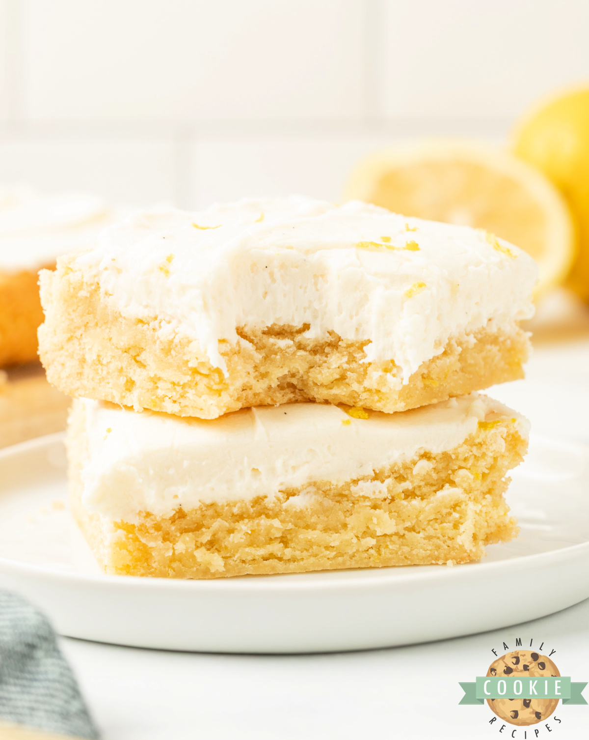 Stack of two lemon cookie bars with cream cheese frosting.