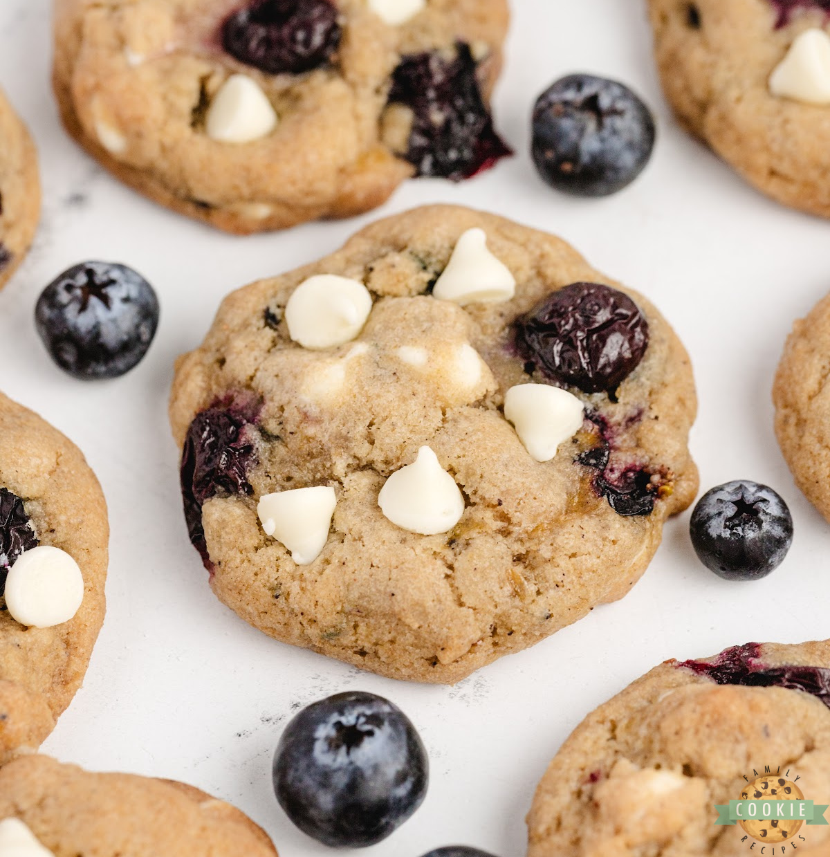 Soft brown butter blueberry cookies with golden edges and juicy blueberries on a white plate.