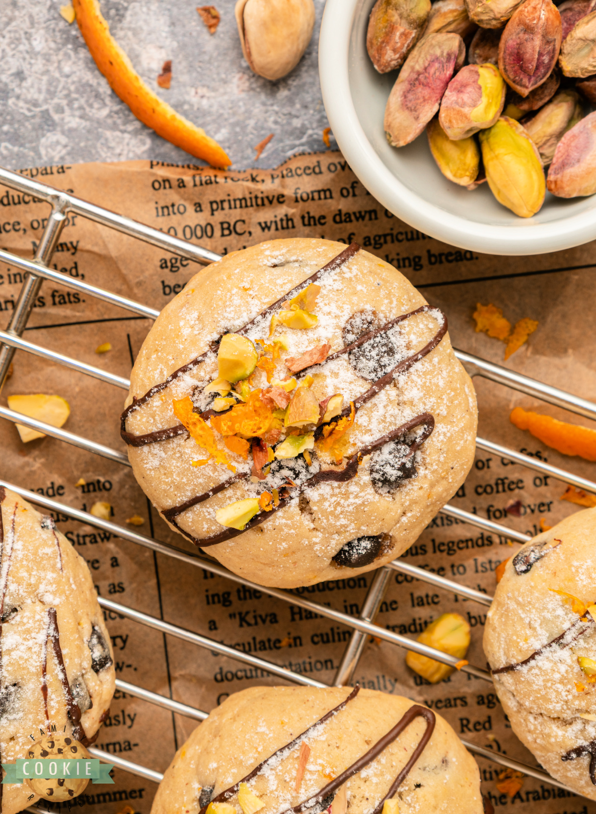 Overhead view of cannoli cookies arranged on parchment paper with pistachios and chocolate chips.
