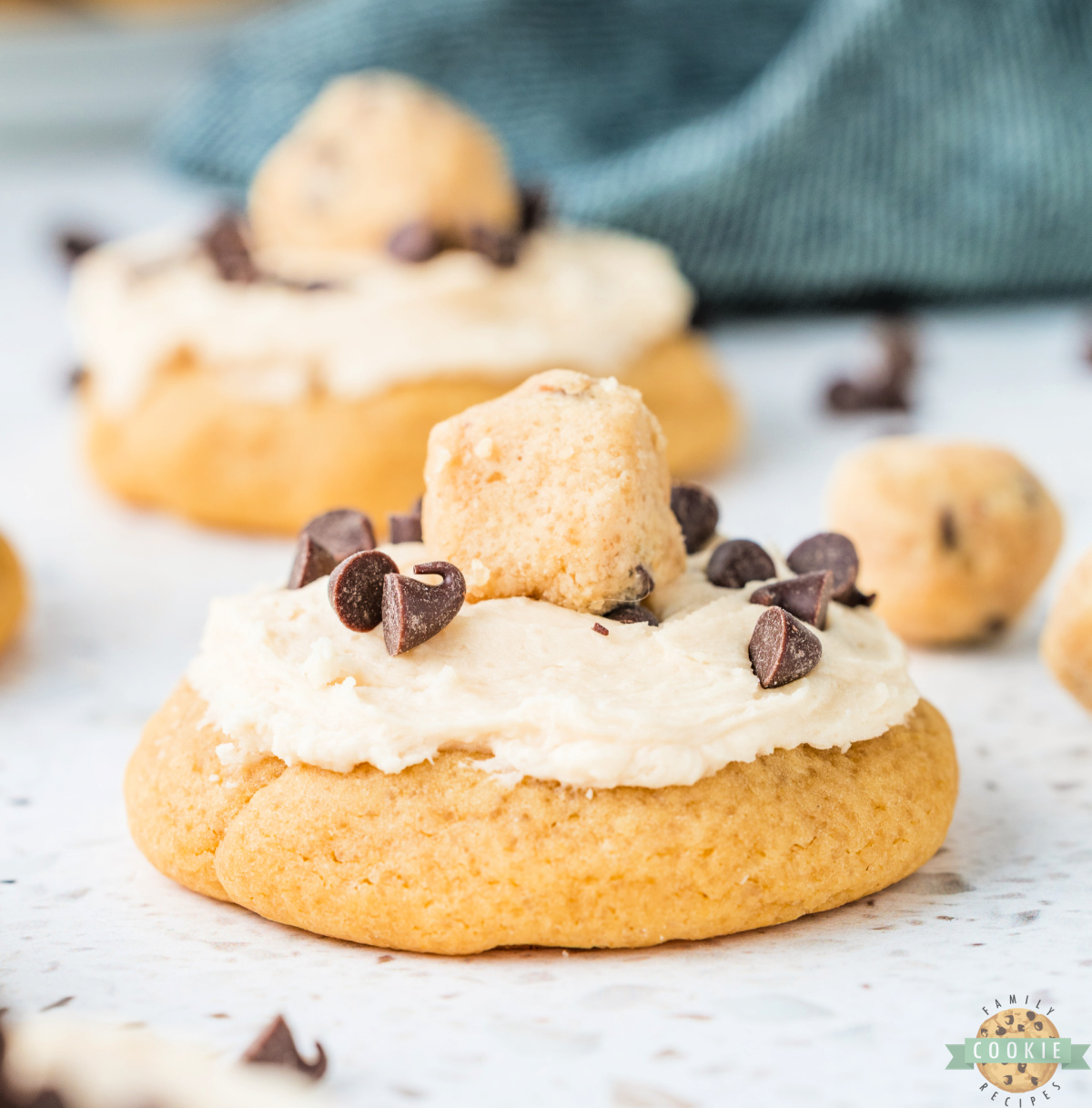 Close up of a cookie dough frosted cookie with creamy frosting and mini chocolate chips on top