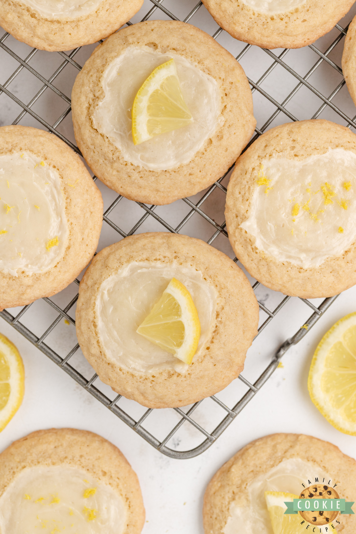 Lemon cheesecake cookies cooling on a wire rack with fresh lemons.
